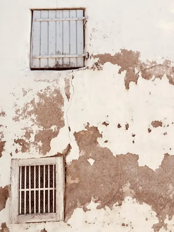 Mur d’enduit usé dont la sous-couche apparaît