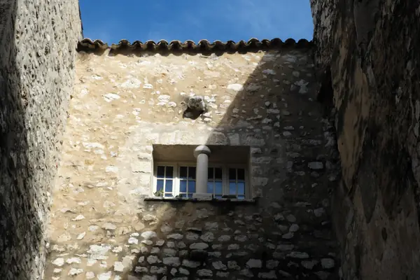 Mur en pierre appareillée d’une maison de village, fenêtre à encadrement clair